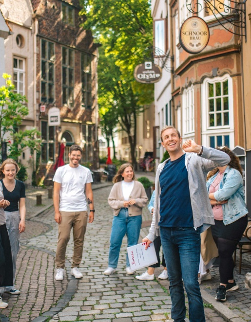 Eine Personengruppe läuft bei einer Stadtführung durch den Bremer Schnoor. Der Gästeführer erklärt etwas.