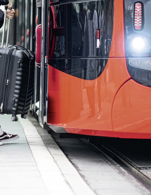 A woman with a suitcase gets on a tram.