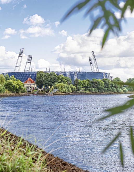 Das Weserstadion an einem Fluss umgeben von grüner Natur.