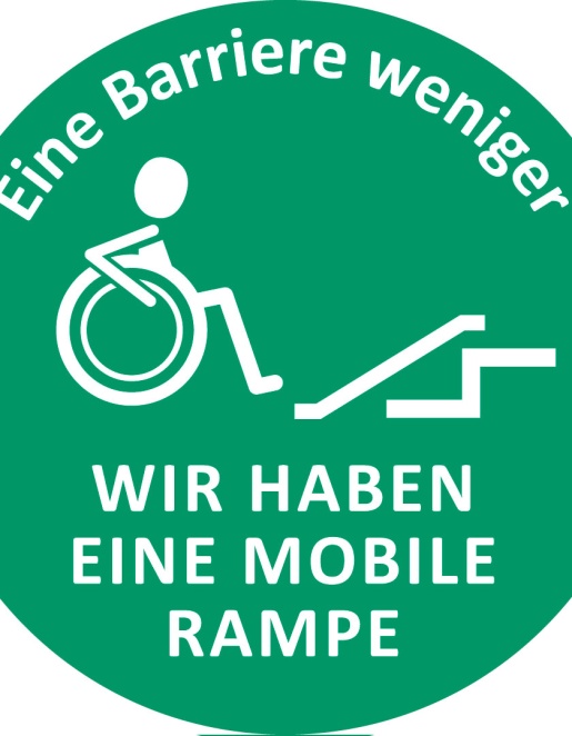 Ein runder grüner Aufkleber mit Aufdruck: Grafik eines Menschen im Rollstuhl vor einer Rampe. Schriftzug "Eine Barriere weniger - Wir haben eine mobile Rampe".