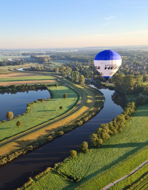 Ein Heißtluftballon fliegt über die grünen Flächen Bremens