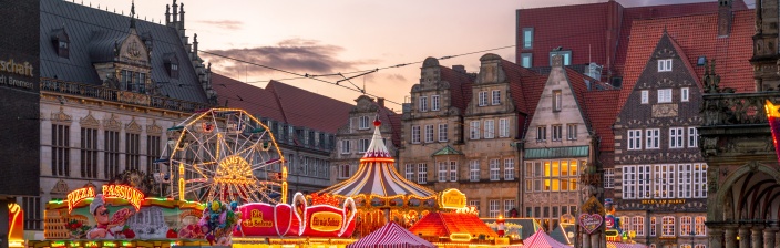 Ein Riesenrad, Buden, Lichter und Menschen auf dem Bremer Marktplatz mit historischer Kulisse.