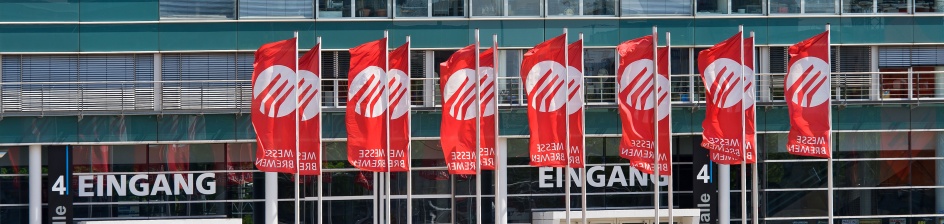 Vor Halle vier wehen rote Fahnen mit der weißen Aufschrift "Messe Bremen".