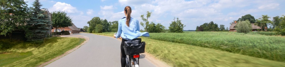 Eine Frau fährt mit einem Rad durch die Natur.