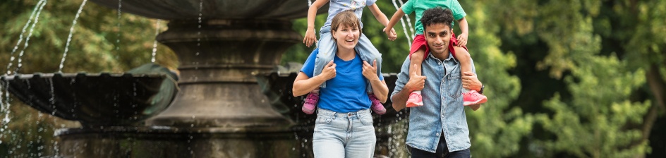 Das Foto zeigt eine Familie, die vor dem Marcusbrunnen im Bürgerpark Bremen steht.