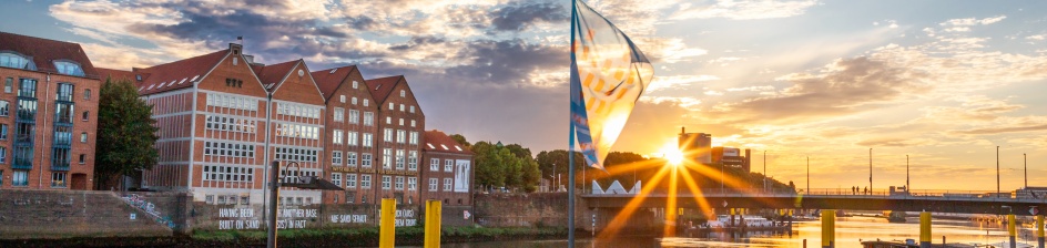 Ein Schiff liegt an der Schlachte, die Sonne geht langsam unter.