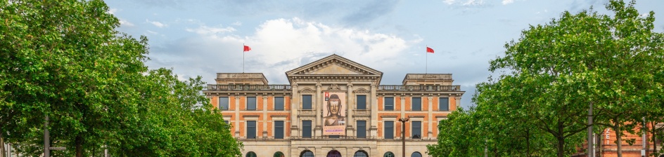 Das Bild zeigt das Gebäude des Übersee-Museums mit seiner altertümlichen Fassade und den Vorplatz mit grünem Rasen.