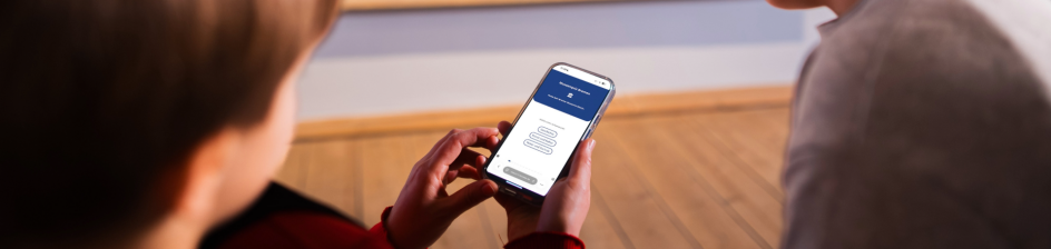 Kinder mit einem Handy in einem Kunstmuseum. Auf dem Handy machen sie das Museenquiz.