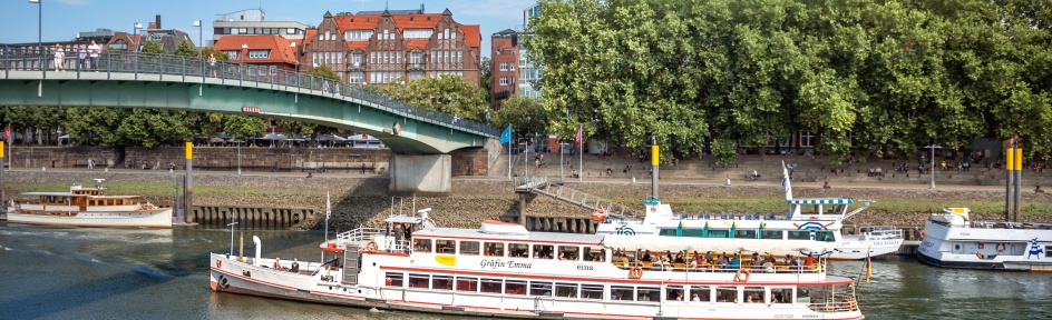 Ein Schiff fährt in der Weser bei einer Brücke. 