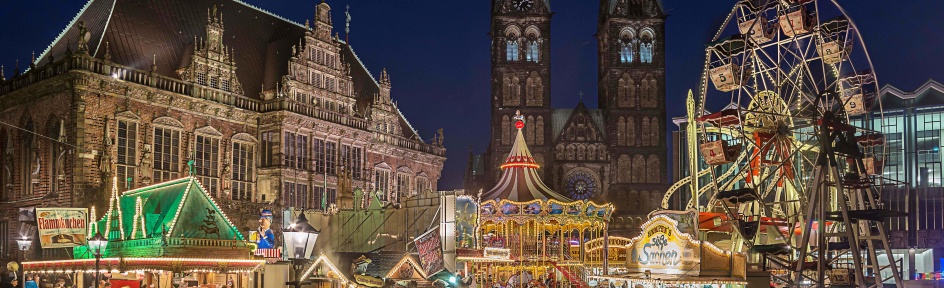 Beleuchtete Buden und Fahrgeschäfte vor der abendlichen Kulisse des Bremer Rathauses