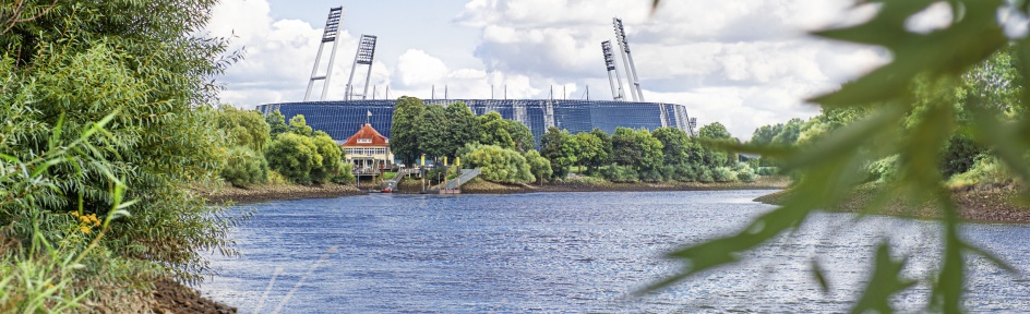 Das Weserstadion an einem Fluss umgeben von grüner Natur.