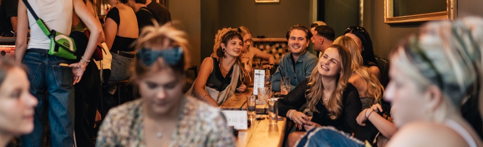 Das Foto zeigt Menschen, die in einer Bar sitzen und Spaß haben.