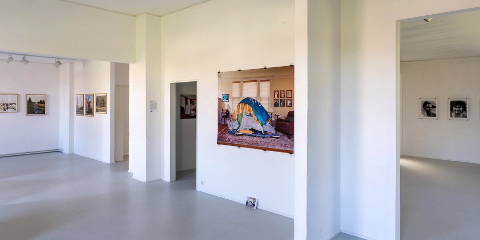 Ein weißer Galerieraum mit Bildern von Fotografien an den Wänden