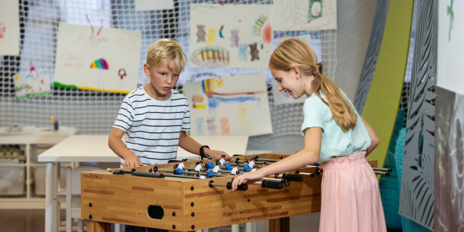Zwei Kinder spielen im Pöks zusammen Tischkicker.