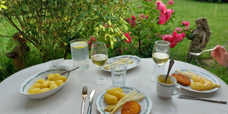 In einem Garten wurde Spargel mit Kartoffeln und Schnitzel serviert.