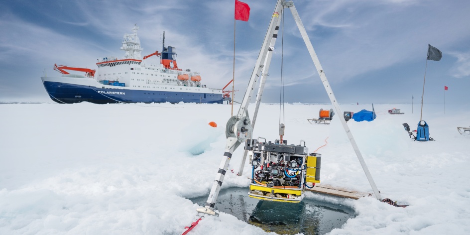 Das Forschungsschiff Polarstern im Eis. Im Vordergrund sind Forschungsutensilien zu sehen.