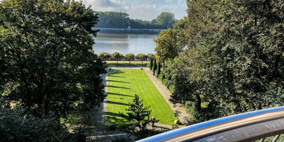 Von einer Aussichtsplattform kann man über einen Park gucken. Im Hintergrund ist die Weser zu sehen. 
