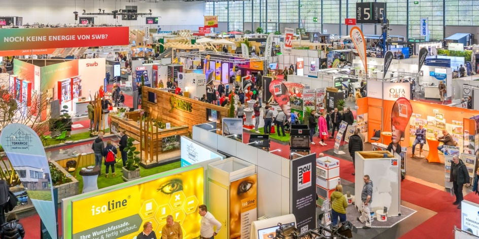 Foto der Messehalle mit verschiedenen Ständen und Aussteller*innen