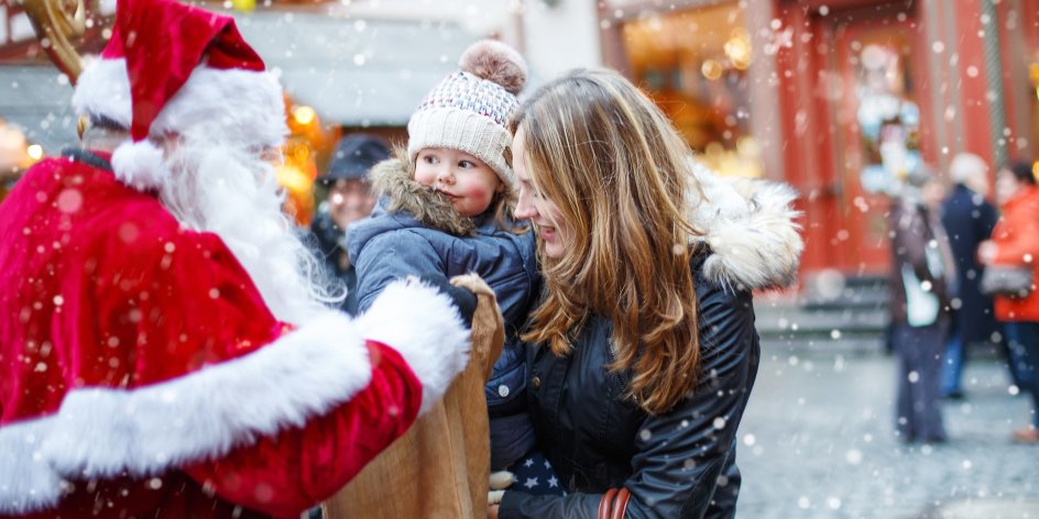 Ein Nikolaus mit einem großen Beutel beschenkt ein kleines Kind. 