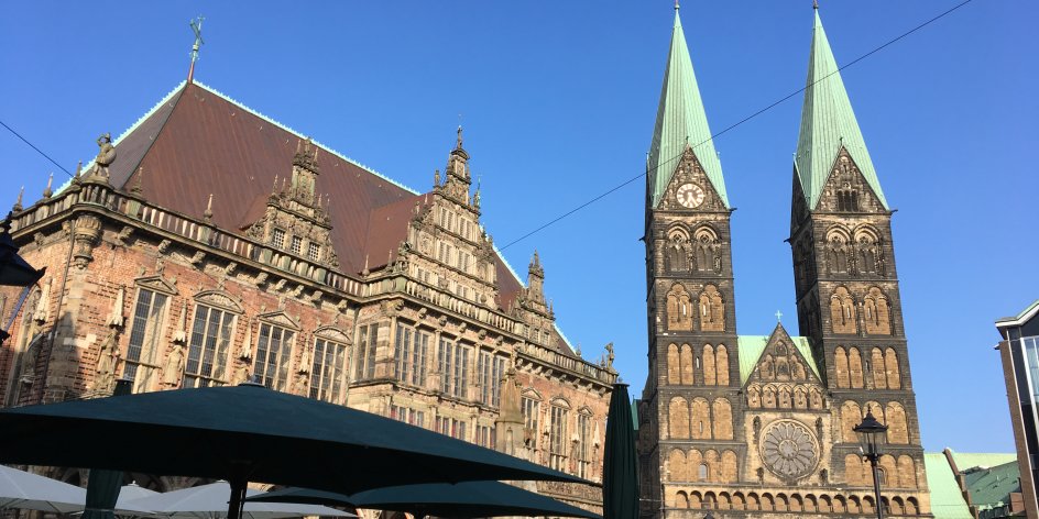Das Bremer Rathaus und der Bremer Dom und der Marktplatz, auf dem Leute in einem Café sitzen 