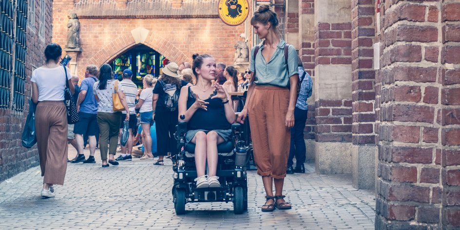Zwei Frauen in der Böttcherstraße. Eine von ihnen sitzt im Rollstuhl.