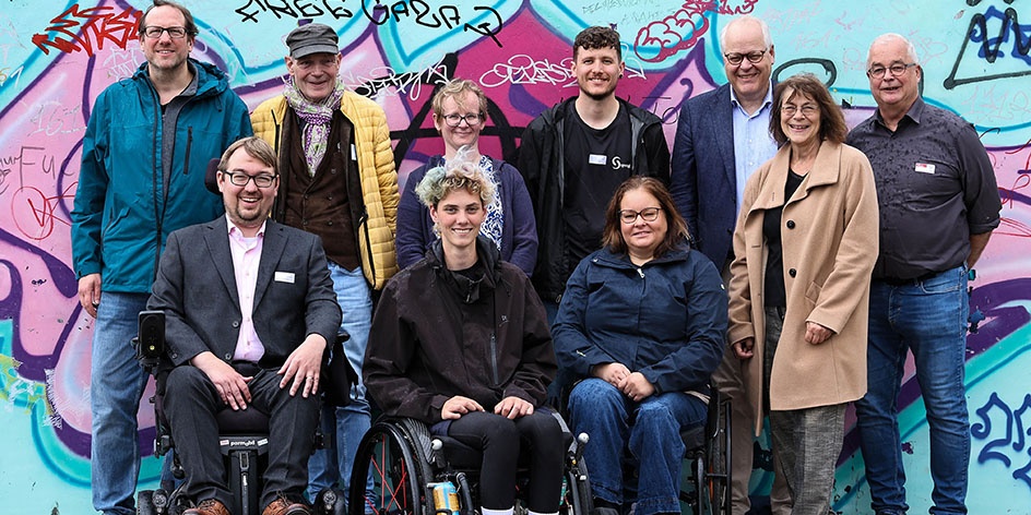 Gruppenbild von den Teilnehmenden der Gesprächsrunde vor einer Graffitiwand. 