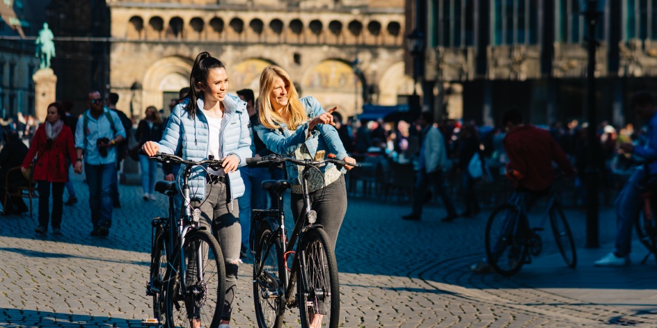 Zwei junge Frauen schieben auf dem Bremer Marktplatz ihre Fahrräder