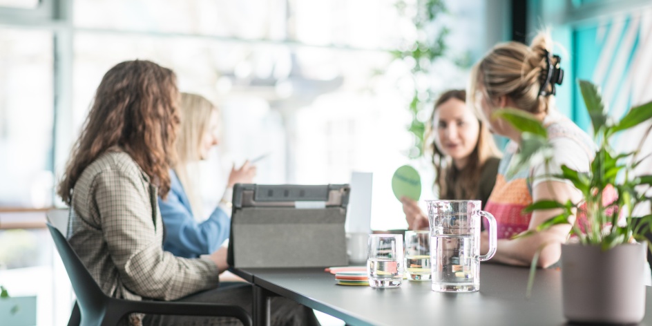 Vier Frauen sitzen gemeinsam an einem Tisch und erarbeiten ein Thema zusammen
