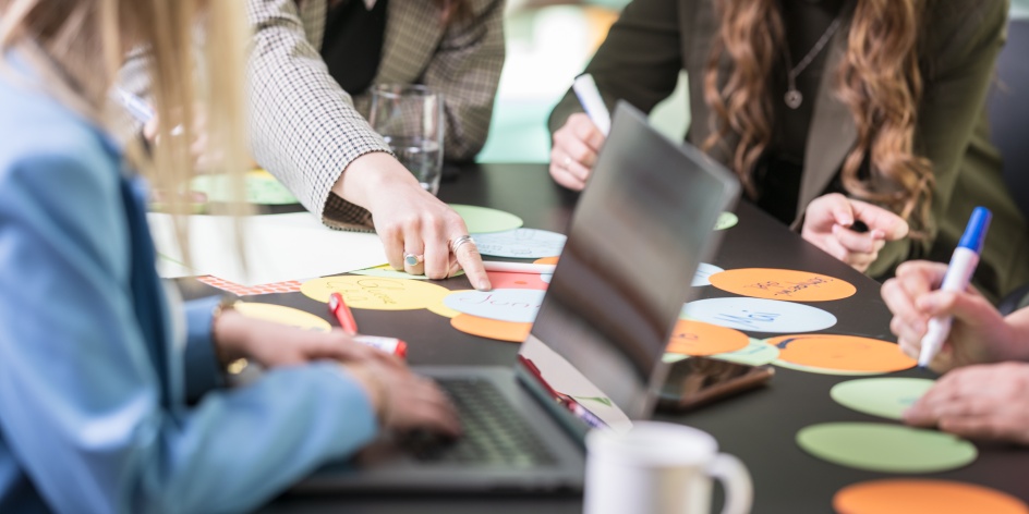 Zahlreiche Hände arbeiten mit handgeschriebenden Post It's