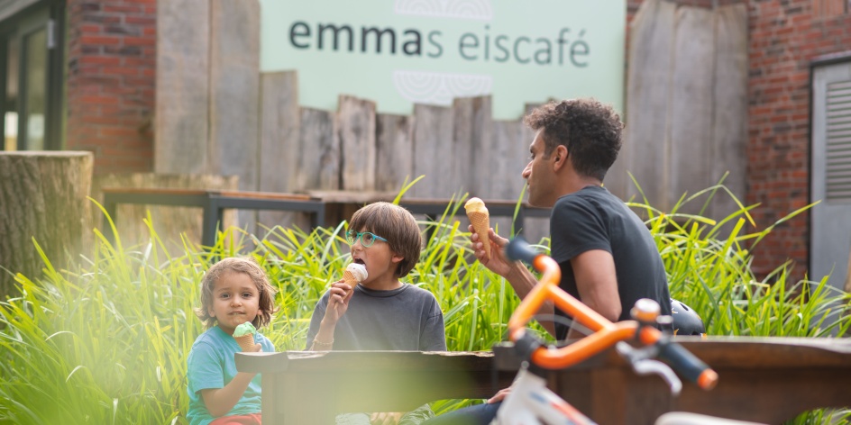Eine Familie sitzt vor einem café und isst Eis.