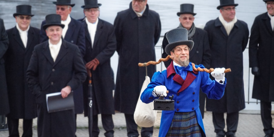 Ein Mann steht in einem Kostüm an der Weser und hält ein Bügeleisen in die Luft. 