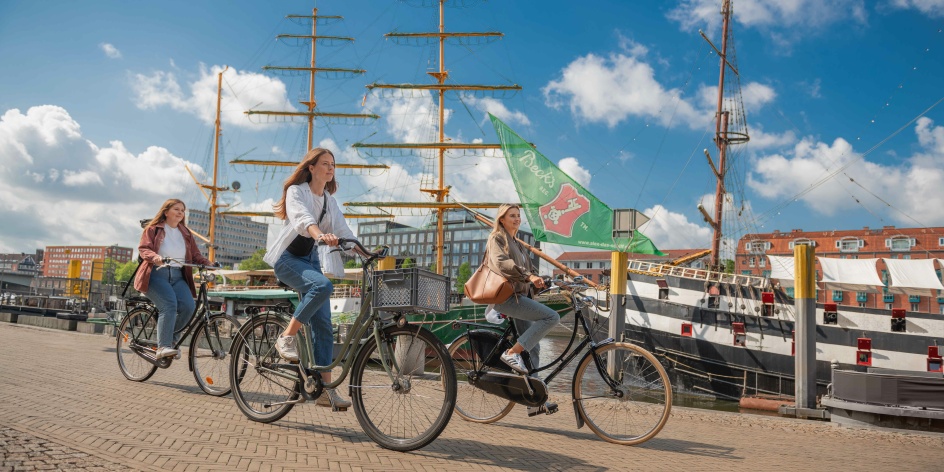 Drei Personen fahren mit dem Fahrrad an der Bremer Schlachte entlang.