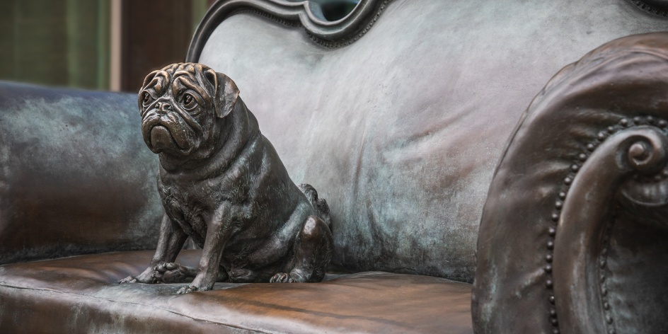 Eine Mops-Statue sitzt auf einer Couch