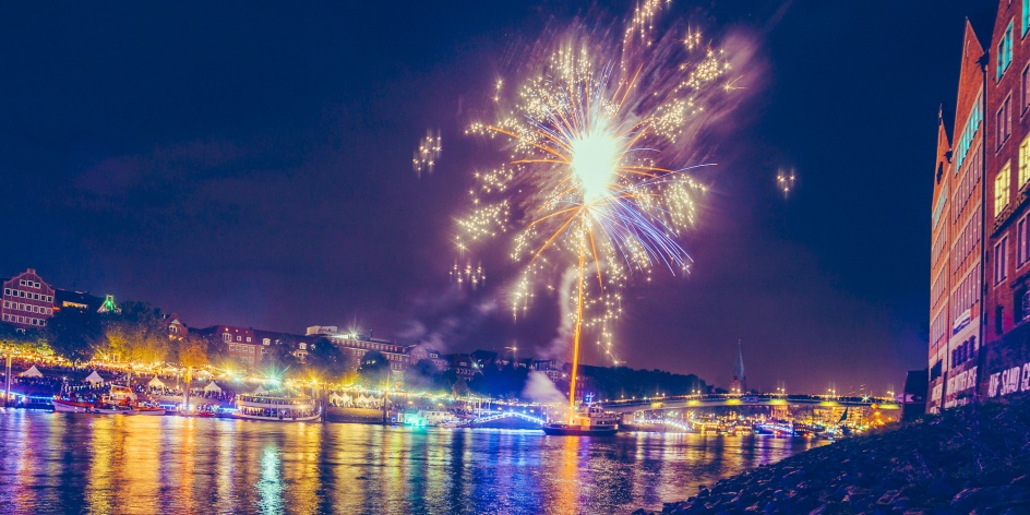 Die Schlachte ist bunt beleuchtet und ein Feuerwerk fliegt in den Himmel. 