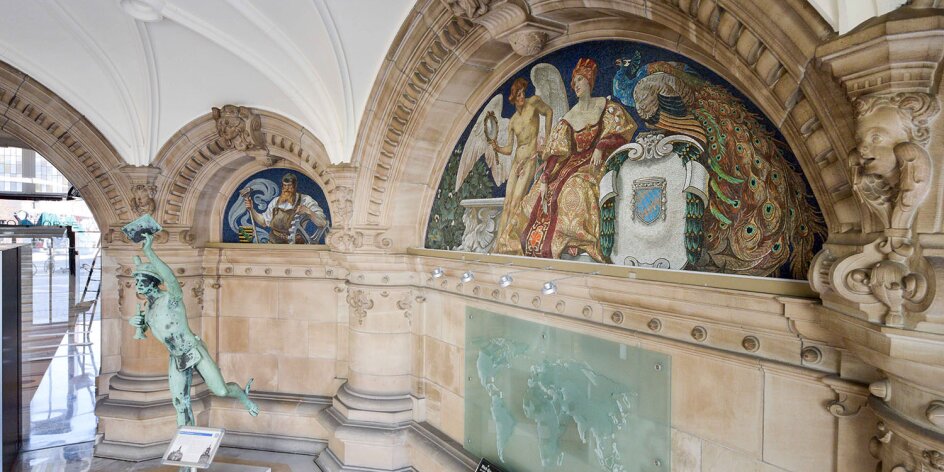 Der prächtige Eingangsbereich der Bremer Baumwollbörse mit bunten Wandmosaiken. In der Halle steht auch eine große Bronzefigur, der Hermes, Gott der Kaufleute.
