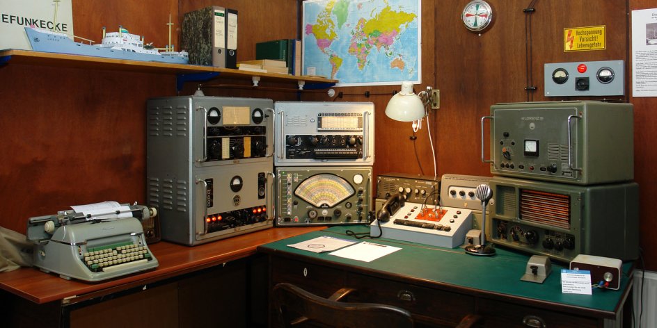 Ein Schreibtisch mit älteren Rundfunkgeräten.