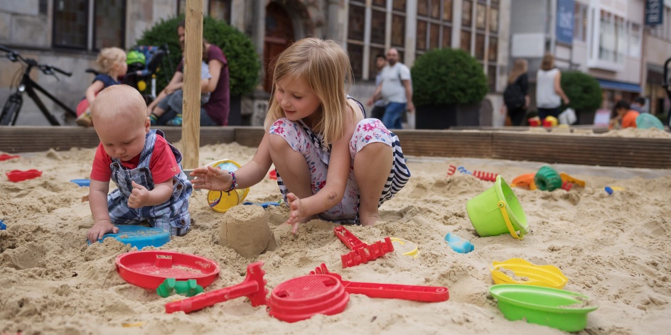 Spielende Kinder in einem Sandkasten.