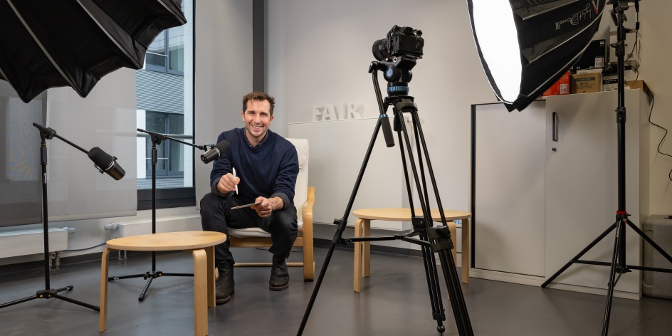Ein Mann sitzt in einem Fotostudio mit Kamera und Licht.