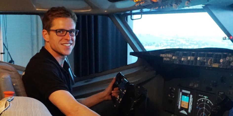 Christian Siegmund lächelt im Flugsimulator in die Kamera.