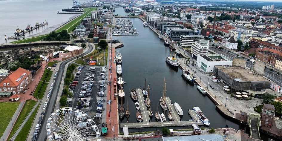 Das Hafenbecken in Bremerhaven von oben. Es liegen Boote im Becken. Am Rand steht ein Riesenrad. 