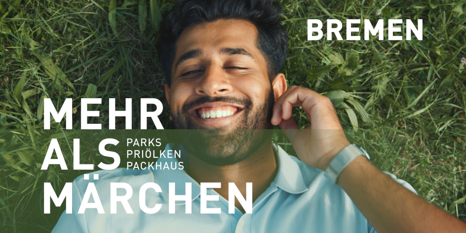 Ein lachender Mann vor einem Beet mit Grünpflanzen. Er hat schwarze Haare und einen leichten Bart. Schriftzug im Bild: "Bremen - Mehr als Märchen. Parks, Priölken, Packhaus".