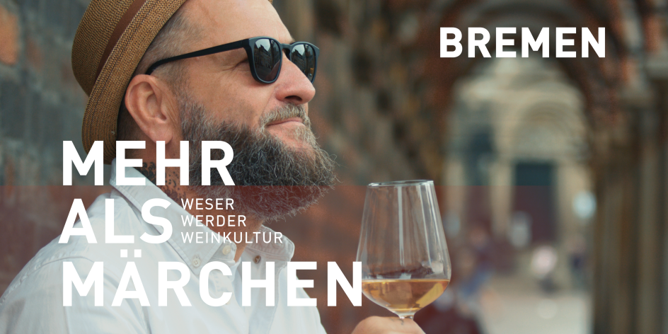 Ein lächelnder Mann vor einem historischen Gebäude. Er hat einen Vollbart, trägt einen Strohhut und eine Sonnenbrille und hält ein Glas mit Weißwein in der Hand. Schriftzug im Bild: "Bremen - Mehr als Märchen. Weser, Werder, Weinkultur". 
