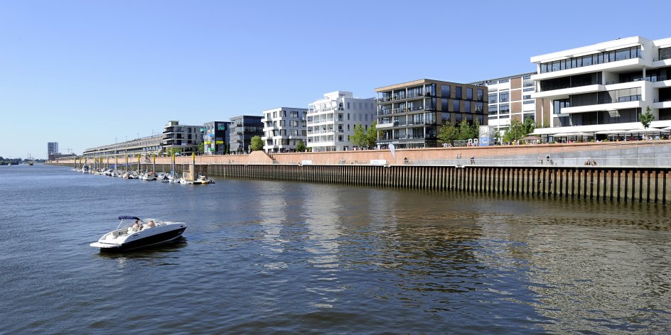 Blick auf den Europahafen, im Vordergrund ein kleines Motorboot auf der Weser, im Hintergrund Büro- und Wohngebäude.