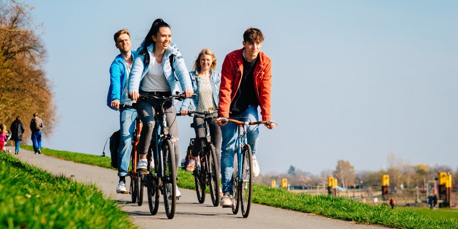 Vier junge Menschen bei klarem Himmel auf ihren Fahrrädern