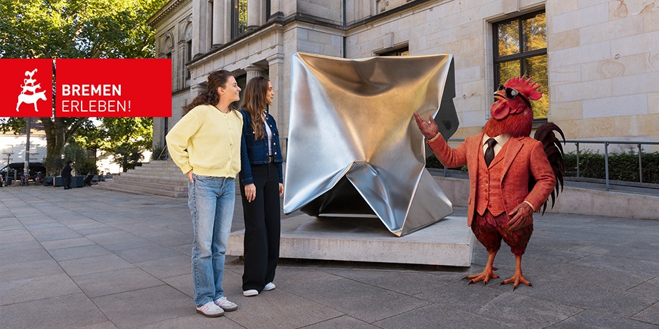Eine künstlich generierte, vermenschlichte Hahn-Figur posiert mit zwei jungen Frauen neben dem Kunstwerk Imploded Cube vor der Kunsthalle Bremen