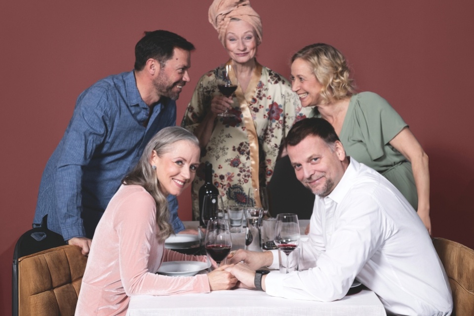 5 Schauspieler an einem Esstisch.