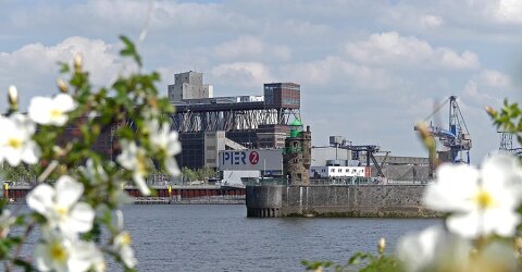 Blick über die Weser auf den Hafen mit der kolossalen Getreideverkehrsanlage, dem Pier 2 und dem Molenturm