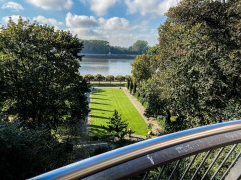 Von einer Aussichtsplattform kann man über einen Park gucken. Im Hintergrund ist die Weser zu sehen. 