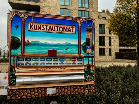 Ein buntbemalter Automat steht vor einem Wohnhaus. 