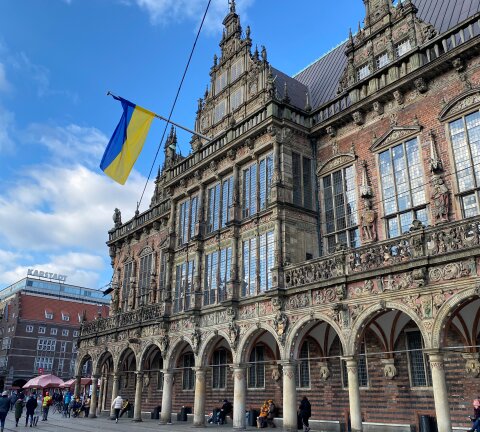 Vom Bremer Rathaus hängt eine ukrainische Flagge hinab.